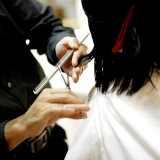 女性の髪をカットする美容師